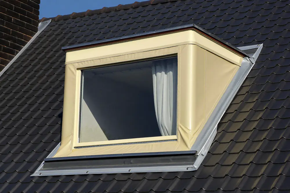 Dakkapel met een afgewerkte dakbedekking en een zinken randafwerking op een donker pannendak