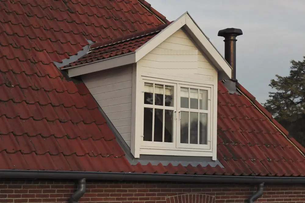 Houten dakkapel met roedenramen in een gebroken wit op een rood pannendak
