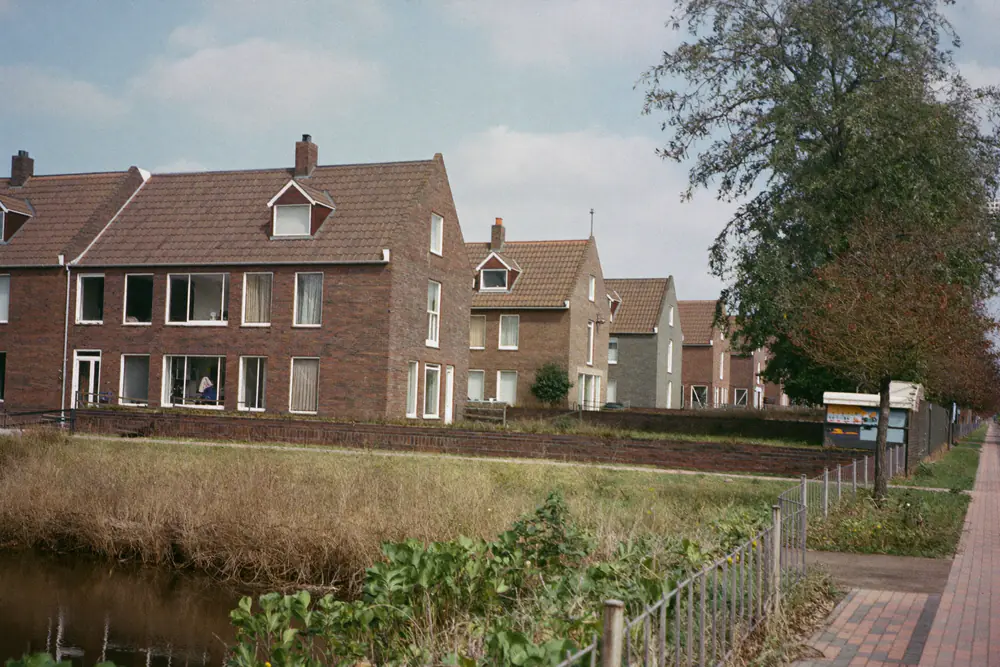 Straat met bakstenen rijwoningen langs een sloot in een Zuid-Hollandse plaats